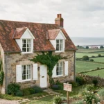 Petite maison en pierre normande à vendre avec vue mer sur la Manche depuis une colline verdoyante