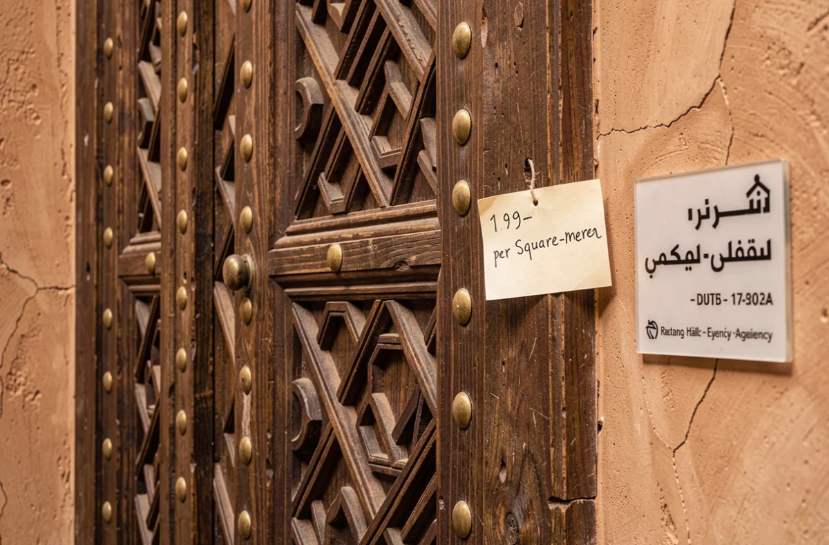 Détail d'une porte en cèdarwood sculptée d'un riad à vendre à Marrakech avec affichage du prix au m², symbole du marché immobilier de la médina en 2026